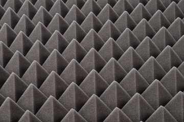Dark gray triangular acoustic and studio sound proof foam pattern texture. Shock proof foam. Selective focus. 