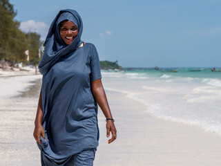 Czarna kobieta idzie brzegiem oceanu Zanzibar - obrazy, fototapety, plakaty
