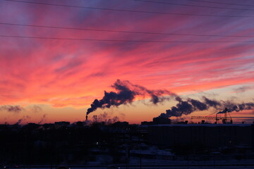 Fantastic beautiful colorful bright sunset in the city and smoky pipes