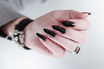 Woman's hands with long nails and black manicure with bottles of nail polish