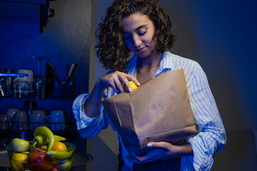 woman taking lemon out of recyclable paper bag and putting it on counter