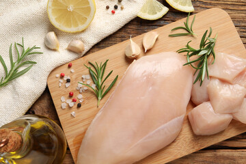 Flat lay composition with fresh raw chicken breast on wooden table.