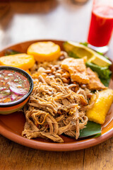 Hornado pork, a typical dish from Ecuador that also has mote, corn, potato tortillas and a sweet and sour sauce with tomato and onion called agrio
