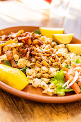 Mote con chicharrón, corn with pork skin in a clay bowl with potatoes and toast. Traditional dish