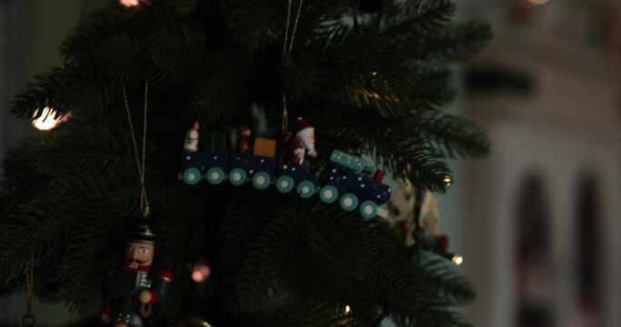 Soft focus to faux Christmas tree decorated with retro Christmas ornaments and lamp garland. Antique nutcracker toy and clown statuette on Christmas tree top. Tilt 4K footage with rack focus
