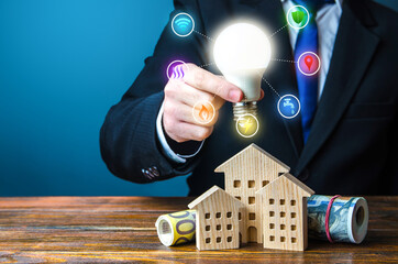 Man holding a light bulb over the house. Electricity, water, gas, heating, internet, security and...