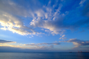 明け方の冬の海。太陽が昇り雲の間から顔を出し、水面はキラキラと輝く。兵庫県芦屋市芦屋浜で撮影。