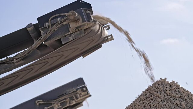 Mobile portable crushing screening plant. Mining conveyor belt sorts rock and loading stones in truck. Heavy machinery working for minerals extraction. Mining extractive industry.