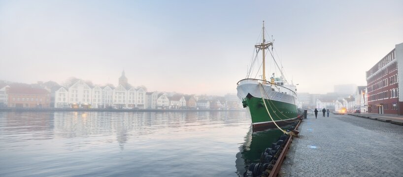 Green training ship moored to a pier in a city center. Stavanger embankment, Norway. Travel destinations, sightseeing, landmark, tourism, cruise, regatta, expedition, research, work, traditional craft