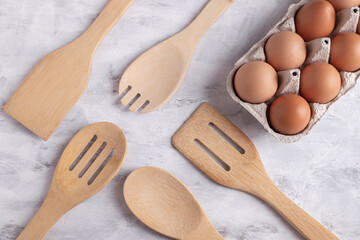 Wooden tools for cooking and chicken eggs on a gray background, top view. Organic Farmed Products. Homemade baking concept