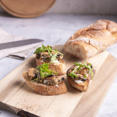 Bread with seafood decorated with rucola. Toast with mussels on a wooden board. Rustic style appetizer. Mediterranean diet. Healthy snack