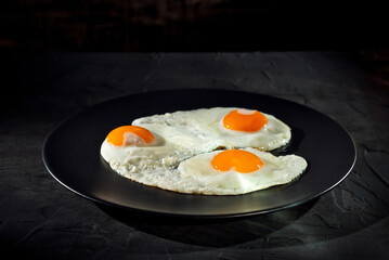 Scrambled eggs in a black plate. Fried eggs on an old concrete table.