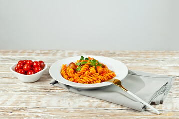 Pasta with meat and tomatoes in a white plate. Pasta on a shabby wooden table. Copy space and free space for text near food.