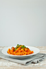 Pasta with meat in a white plate. Pasta on a shabby wooden table. Copy space and free space for text near food.