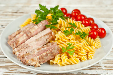 Pasta with meat and tomatoes in a white plate. Pasta on a shabby wooden table.