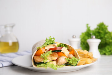 Delicious chicken shawarma and French fries served on white wooden table, closeup