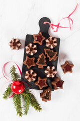 Christmas dessert, chocolate little cakes cookies in the shape of a tree, snowflakes, stars with marmalade filling on a serving board on a white background. Top view