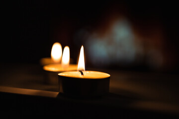 Close up of white burning candles on the mirror with golden light background blur. blackout
