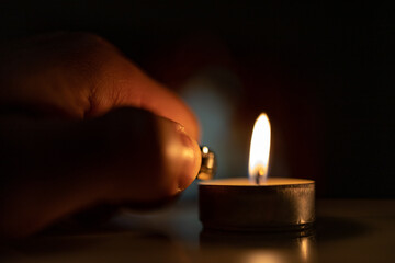 hand lighting a candle with a lighter. blackout 