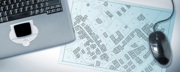 Imaginary cadastral map of territory with buildings and land parcel - concept with laptop computer - Note: the map background is totally invented and does not represent any real place