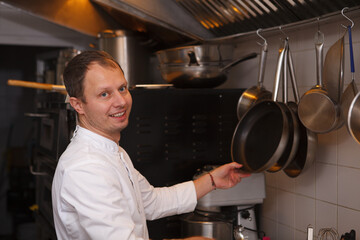 Male chef smiling to the camera while working at the kitchen