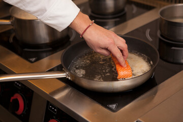 Cropped shot of a chef frying salmon on the pan