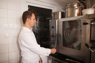 Professional chef using baking oven at his restaurant kitchen