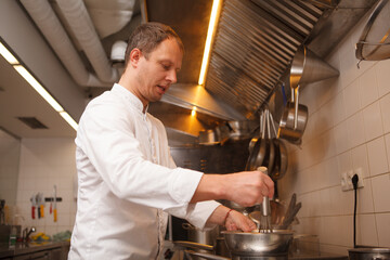 Low angle shot of a chef whisking sauce in a bowl, cooking at the restaurant
