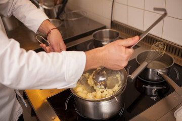 Cropped shot of a chef mashing potatoes, cooking at the kitchen