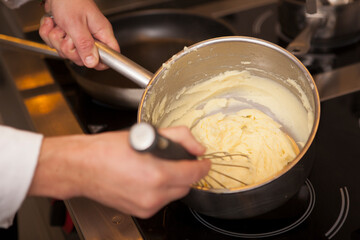 Close up of a chef whisking mashed potatoes in a pot