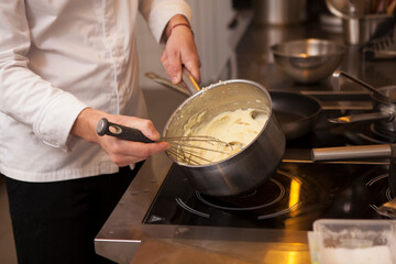 Unrecognizable chef whisking mashed potatoes in a pot, working at restaurant