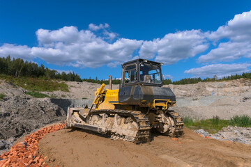 Obraz premium the process of leveling the soil with a modern bulldozer during the construction of a dirt road