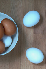 several fresh chicken eggs in a ceramic cup on a wooden background. Healthy eating concept