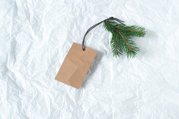 Close up of green fir branch with blank white label. Price tag mockup scene on tissue paper background. Christmas composition, top view, flat lay
