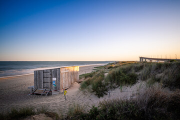 kitesurfing hut at the end of the season at sunrise. bridge of ile de ré in the background. empty...