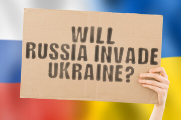 The question " Will Russia invade Ukraine? " on a banner in men's hand with blurred Russian and Ukrainian flag on the background. Terror. Threat. Alliance. Weapon. Armed. Invading. Crisis. Aggression