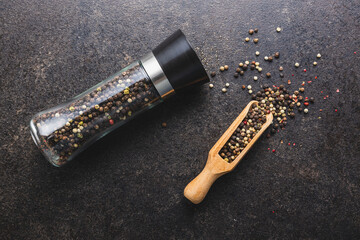 Pepper mill and whole pepper in wooden scoop