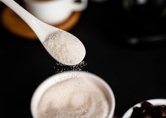 Sugar in spoon on a dark background. Sugar bowl.