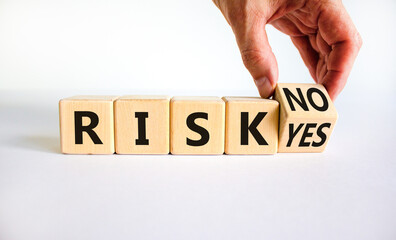 Question about Risk symbol. Businessman turns a wooden cube and changes words 'risk yes' to 'risk no'. Beautiful white table, white background, copy space. Business risk yes or no concept.