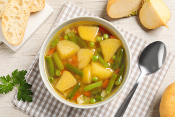 Bowl of delicious turnip soup served on wooden table, flat lay