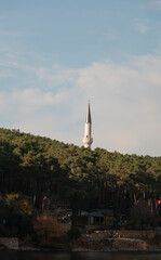 Obraz premium A mosque minaret standing behind forest. Beautiful autumn landscape.