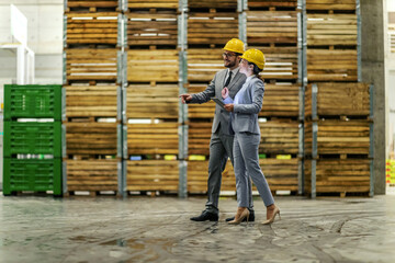 Warehouse business improvement by management supervisions. Business people wear a suit a protective yellow helmet walk in the warehouse. Storage visiting, business owner, small business