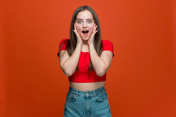 Amazed excited young girl with wow face open mouth stunned shocked surprised with win, fortune on orange background