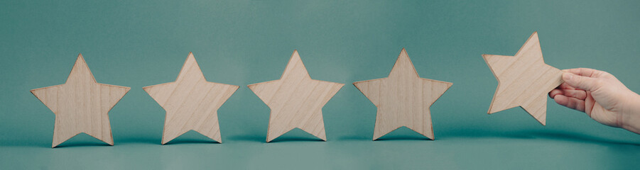 Five stars on a blue colored background, hand put the last star in the row, rating, giving feedback