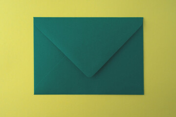 Green envelope on a yellow background. Close-up. - obrazy, fototapety, plakaty