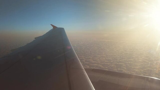 The plane fly in the sunrise sky on the background of beautiful puffy clouds
