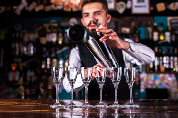 Bearded bartender intensely finishes his creation at bar