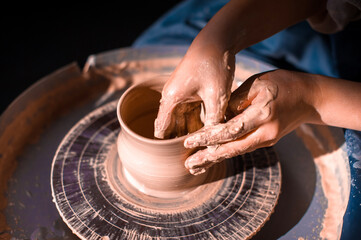 Close-up of potter's hands with the product on a potter's wheel