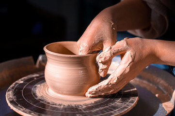 Craftsman's hands and potter's wheel. Close-up.