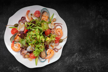 Mix salad with seafood on a dark background